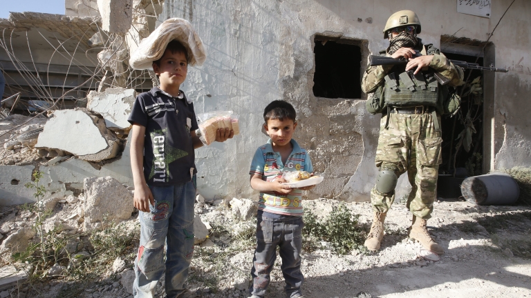 epa05290067 Syrian children holding bread and sweets from a humanitarian aid delivery by the Russian army stand near Russian soldier in a village of Kaukab, Hama province, Syria, 04 May 2016. The United States and Russia have agreed to extend the cease-fire in Syria to the city of Aleppo, the US State Department reported on 04 May.  EPA/SERGEI CHIRIKOV