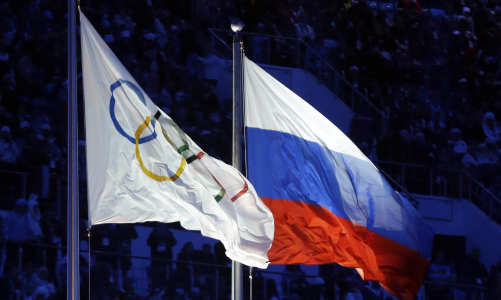 FILE - In this Feb. 7, 2014 file photo the Russian and the Olympic flags wave during the opening ceremony of the 2014 Winter Olympics in Sochi, Russia. The credibility of the fight against doping in sports will be at stake Friday, June 17, 2016 when track and field's world governing body decides whether to uphold or lift its ban on Russian athletes ahead of the Rio de Janeiro Olympics. Sports geopolitics — and the key issue of individual justice vs. collective punishment — frame the debate heading into the meeting of IAAF leaders in Vienna.  (AP Photo/Patrick Semansky, file)