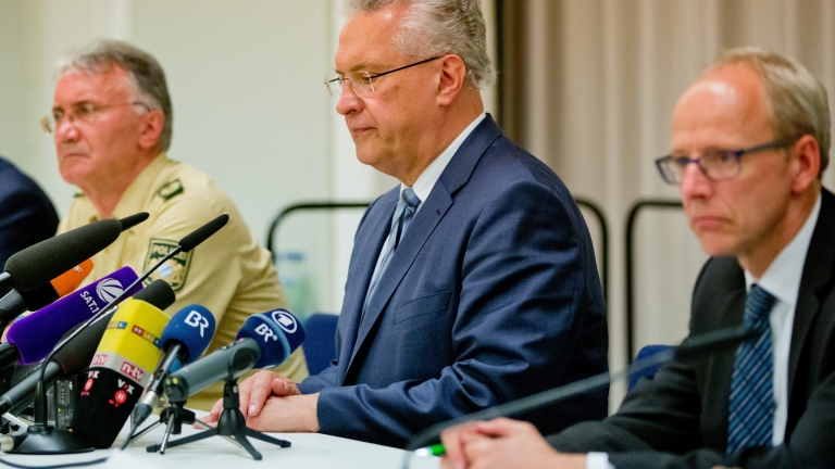 epa05439825 Bavarian Interior Minister Joachim Herrmann (C) speaks during a press conference following an explosion in front of a restaurant in Ansbach, Germany, 25 July 2016. A man was killed and 12 others were injured in an explosion in Franconia Ansbach late on 24 July. According to media reports, a migrant from Syria tried to enter inJoachim Herrmannto a music festival nearby and after he was denied entry into the venue, detonated a device in his backpack in front of a restaurant. The suspect died in the explosion. Around 2,500 people were evacuated from the venue of the festival.  EPA/DANIEL KARMANN