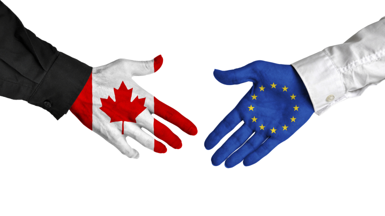 Diplomatic handshake between leaders from Canada and the European Union with flag-painted hands.
