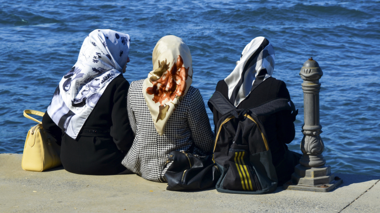 Istanbul, Turkey - October 20, 2013: Sea of Marmara, the Bosphorus. Middle East three women sitting on the beach, looking at the sea resting.