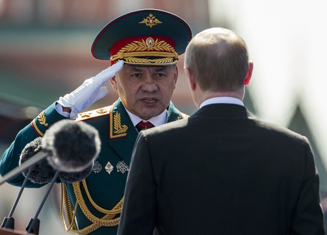 In this photo taken on Monday, May 9, 2016, Russian Defense Minister Sergei Shoigu, left, salutes to Russian President Vladimir Putin, back to a camera, prior the Victory Day Parade on the Red Square, which commemorates the 1945 defeat of Nazi Germany in Moscow, Russia. Shoigu says the airstrikes were suspended starting from 10 a.m. on Tuesday, Oct. 18 and the suspension is intended to prepare for the opening of humanitarian corridors for the rebels to leave the besieged city of Aleppo. (AP Photo/Alexander Zemlianichenko)