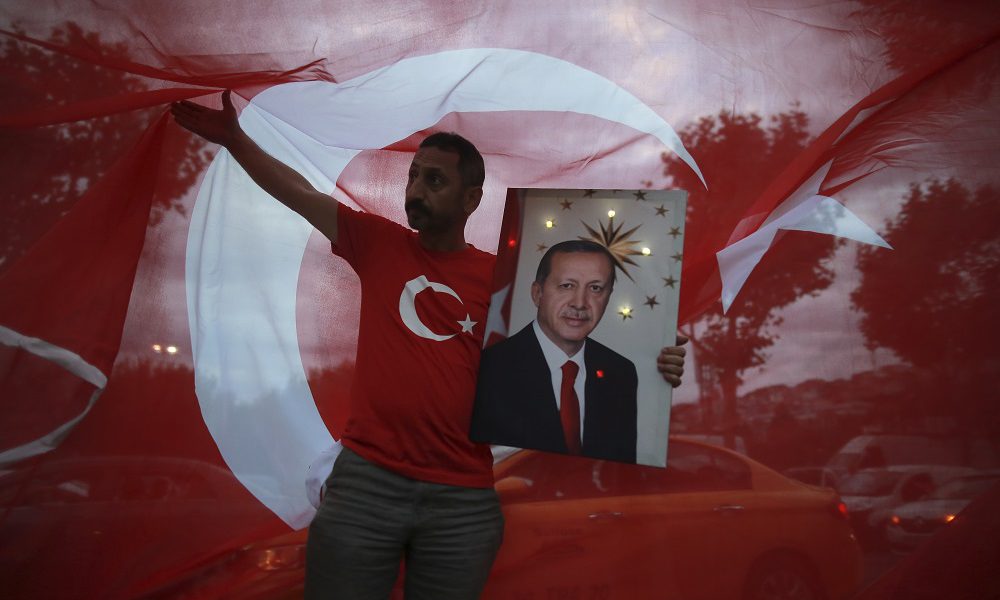 A man hold a picture of Turkey's President and ruling Justice and Development Party, or AKP, leader Recep Tayyip Erdogan while celebrating outside the party headquarters in Istanbul, Sunday, June 24, 2018. Early partial results in Turkey's presidential elections Sunday showed incumbent Recep Tayyip Erdogan in the lead, with challenger Muharrem Ince in second place. (AP Photo/Emrah Gurel)