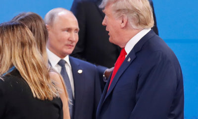 Russia's President Vladimir Putin, left, watches President Donald Trump, right, walk past him as they gather for the group photo at the start of the G20 summit in Buenos Aires, Argentina, Friday, Nov. 30, 2018. Leaders from the Group of 20 industrialized nations are meeting in Buenos Aires for two days starting today.(AP Photo/Pablo Martinez Monsivais)