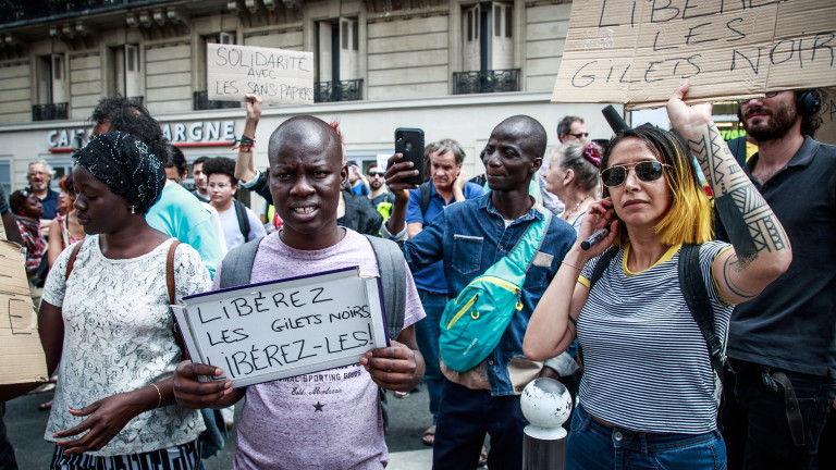 epa07714270 Human rights activists and memebers of the 'Black Vests' movement holds posters reading 'Free Black Vests' as they gather in front of a police station, where other activists have been detained in custody in Paris, France, 13 July 2019.  Hundreds of undocumented migrants calling themselves 'black vests' (gilets noirs) stormed the Pantheon monument in Paris on 12 July 2019 to demand right to stay in France.  EPA/CHRISTOPHE PETIT TESSON