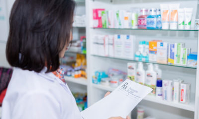 asian female pharmacist checking drug on shelf in pharmacy store Thailand