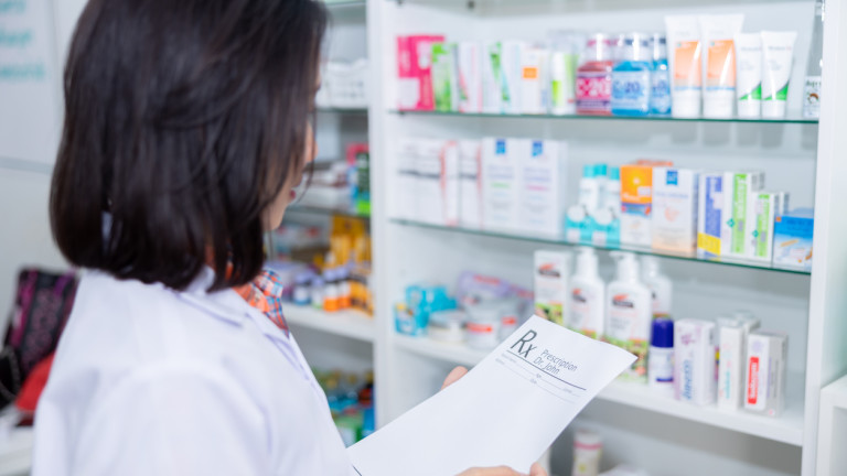 asian female pharmacist checking drug on shelf in pharmacy store Thailand
