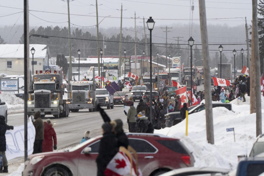 Protesters and supporters against a COVID-19 vaccine mandate for cross-border truckers cheer as a parade of trucks and vehicles pass through Kakabeka Falls outside of Thunder Bay, Ont. on Wednesday, January 26, 2022. THE CANADIAN PRESS/David Jackson